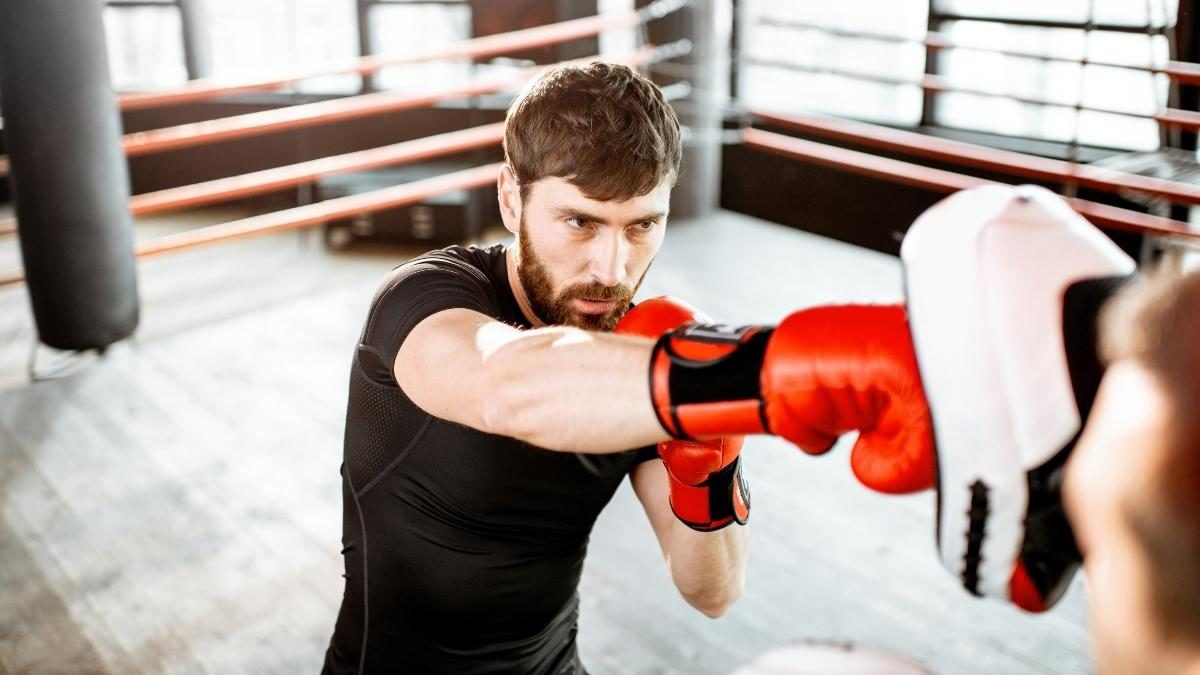 Boxing student improving technique on pads with a coach